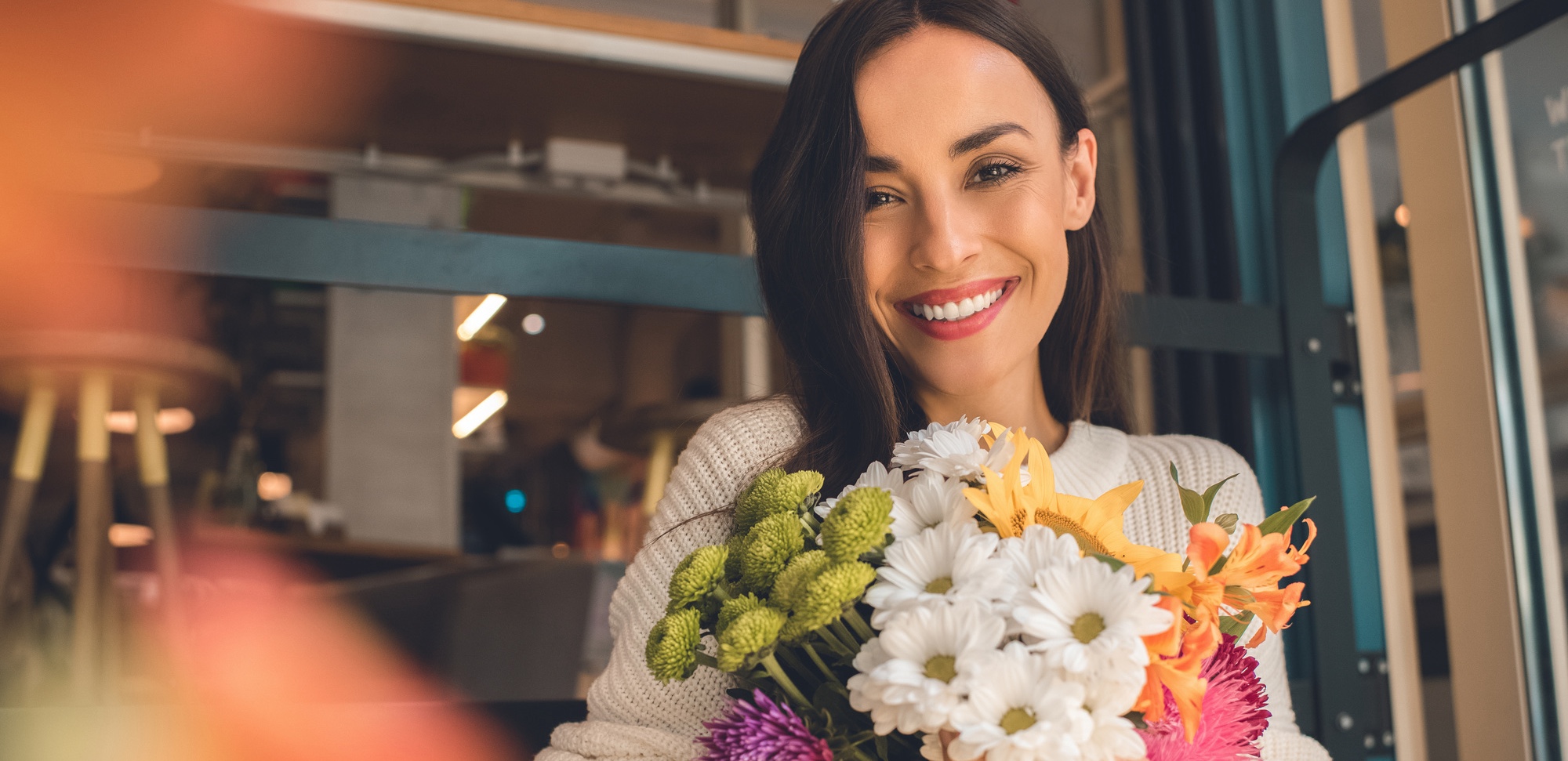 Portrait of smiling young woman holding colorful bouquet from various flowers after PRP female rejuvenation