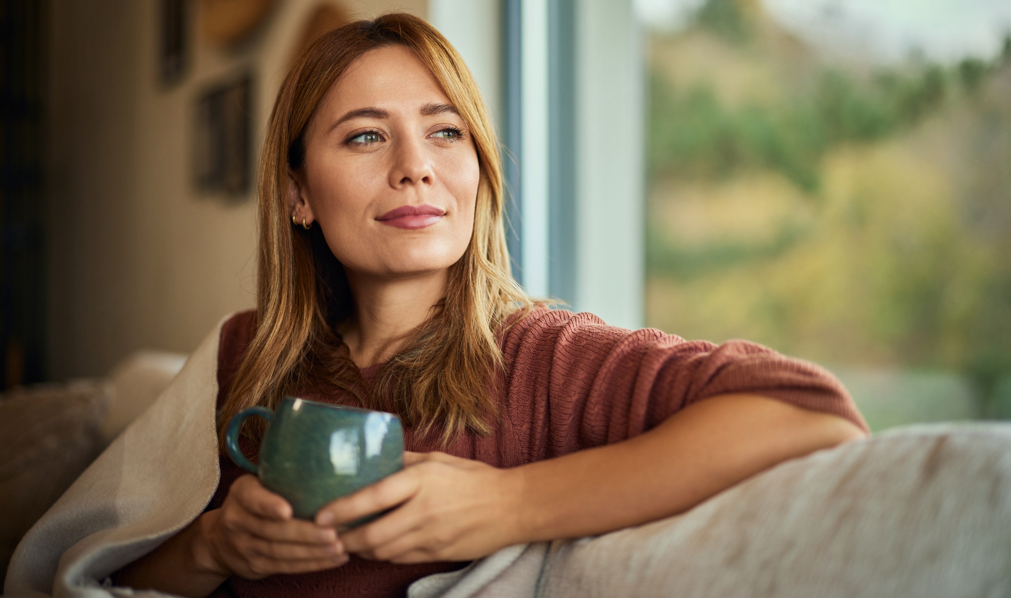 A beautiful blonde woman with gut health issues, enjoying a cup of tea