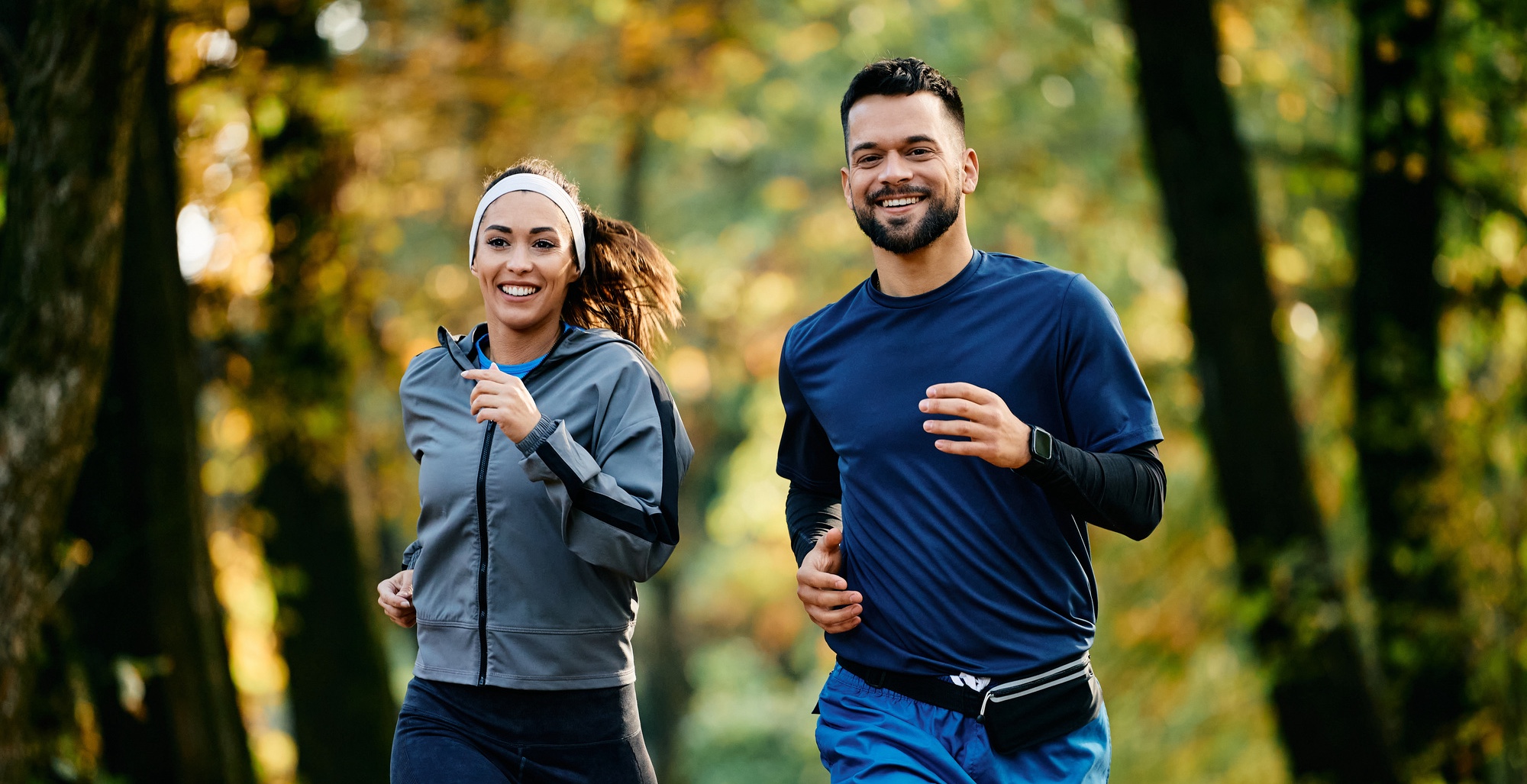 Photo of a happy couple jogging through the woods