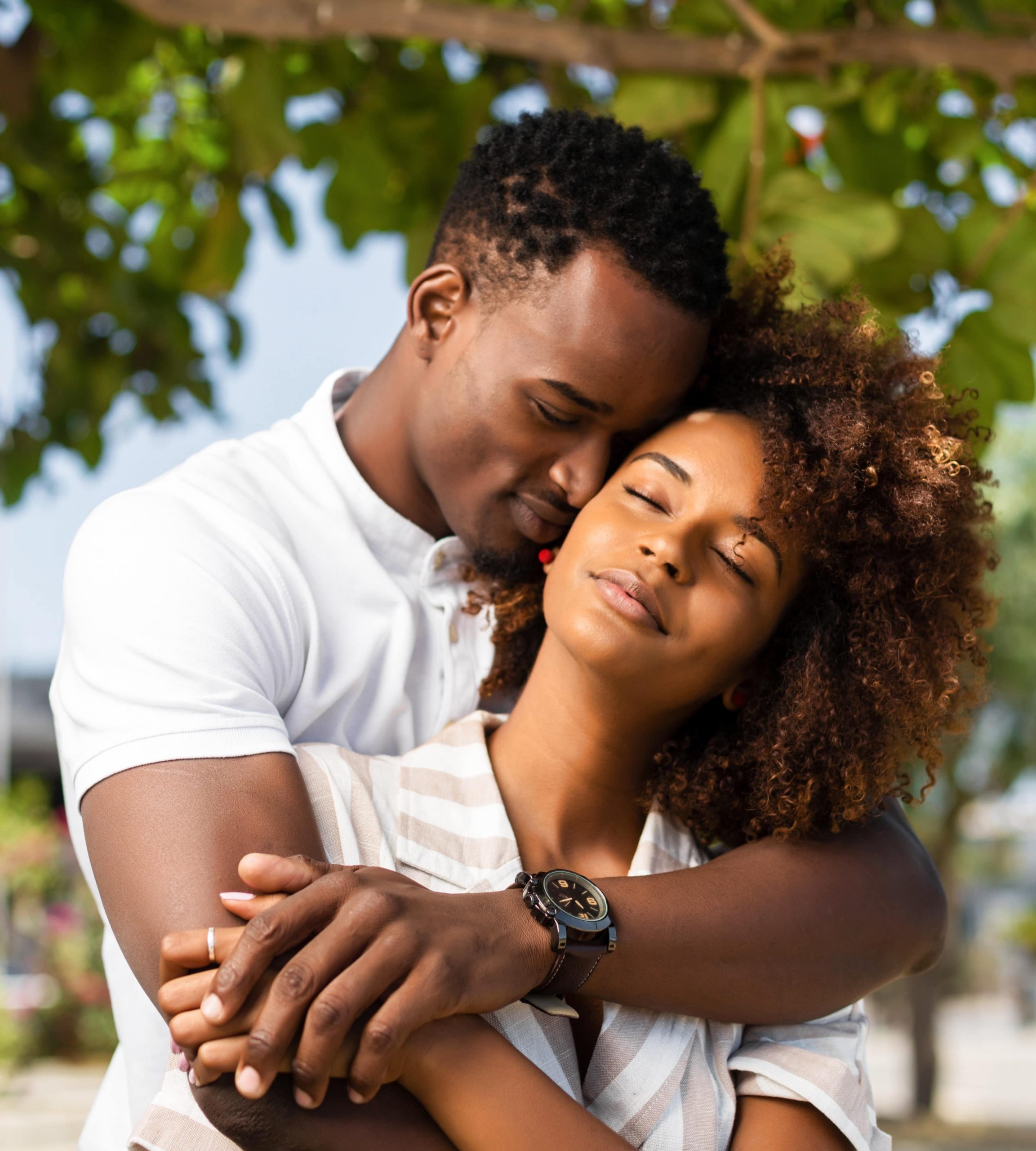 Photo of a man holding his wife. They both look satisfied.