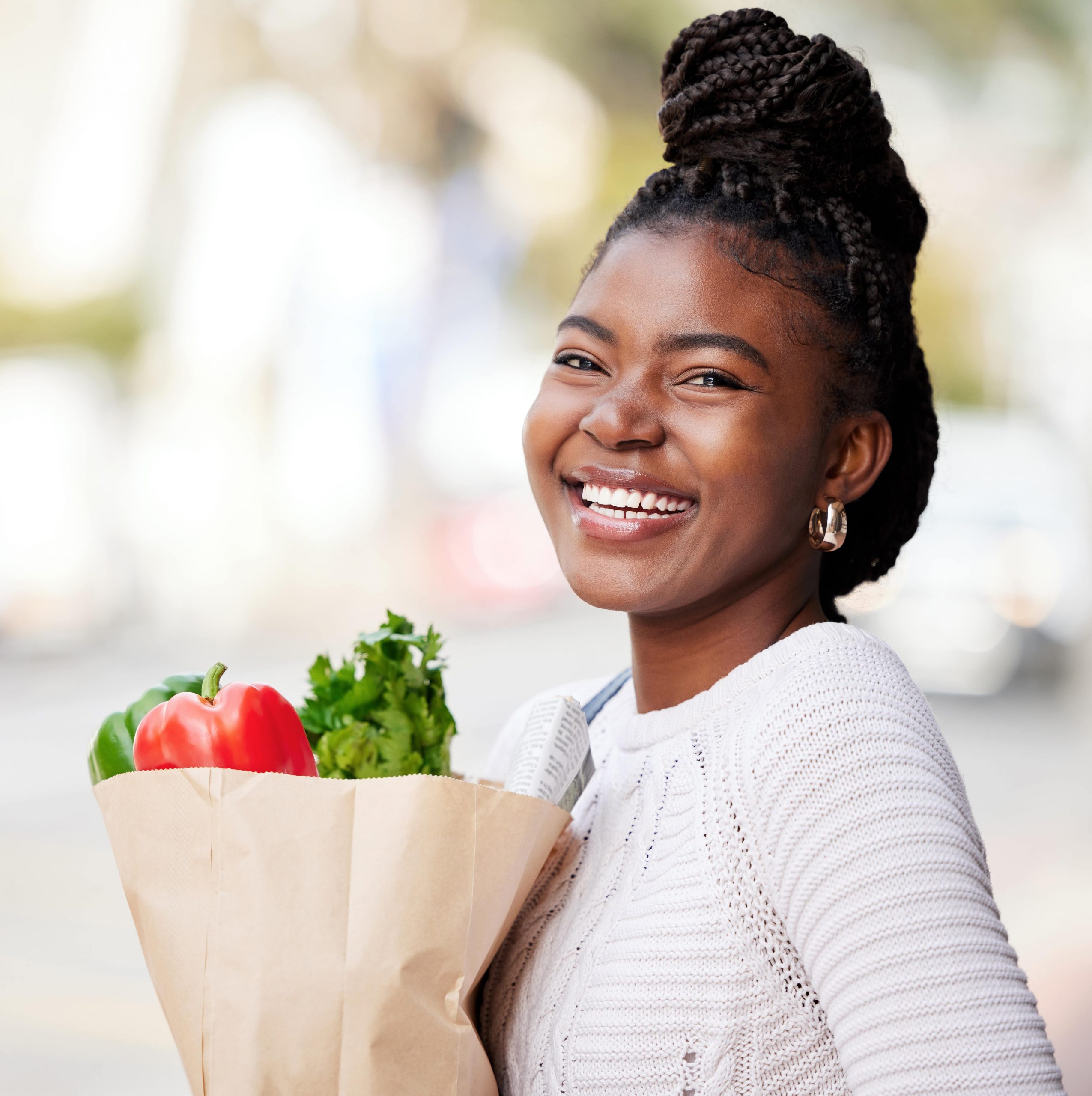 Photo of a smiling woman holding a bag of groceries