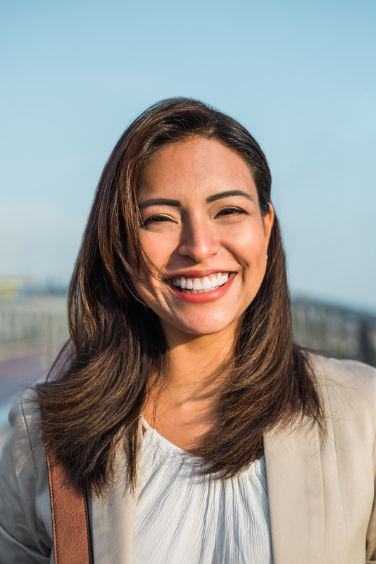 Portrait of a beautiful latin woman smiling outdoors with sunset light.