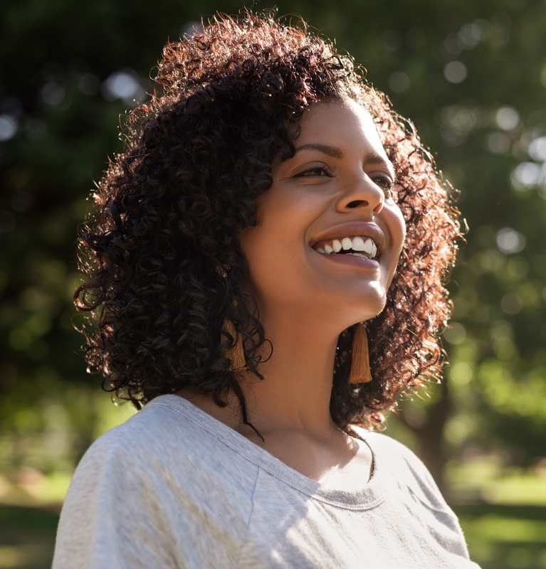 Smiling young woman enjoying a sunny day in the park after dermaplaning treatments