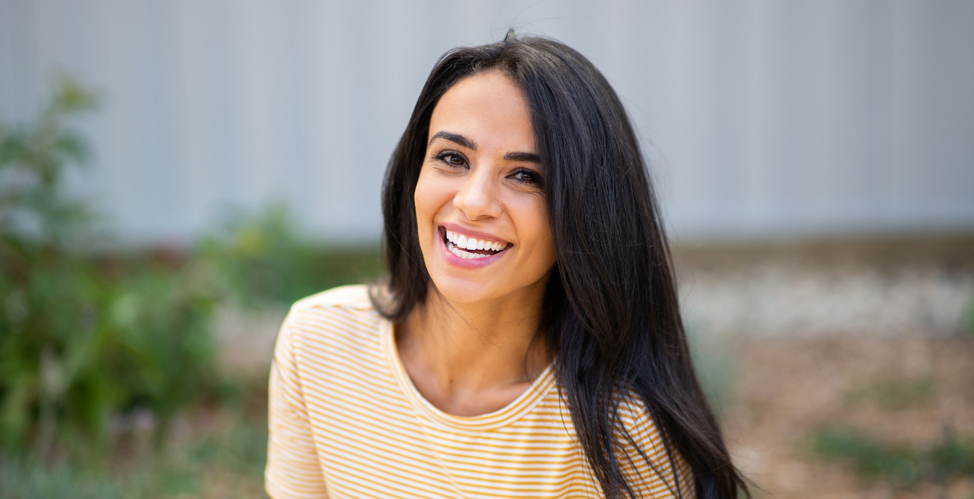 Close up portrait smiling young hispanic woman sitting outdoors after RF microneedling