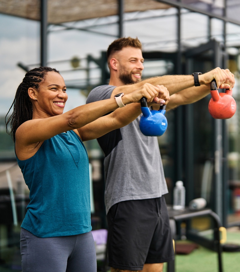 Photo of a woman and man lifting weights at a gym