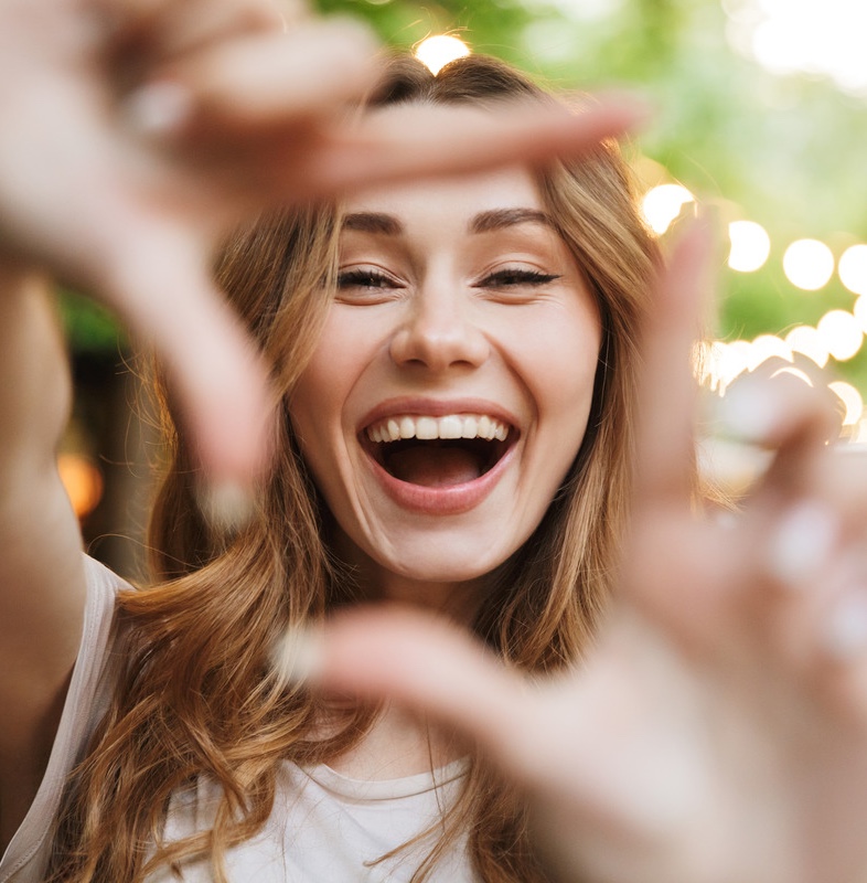 Close up of happy young woman showing frame with fingers