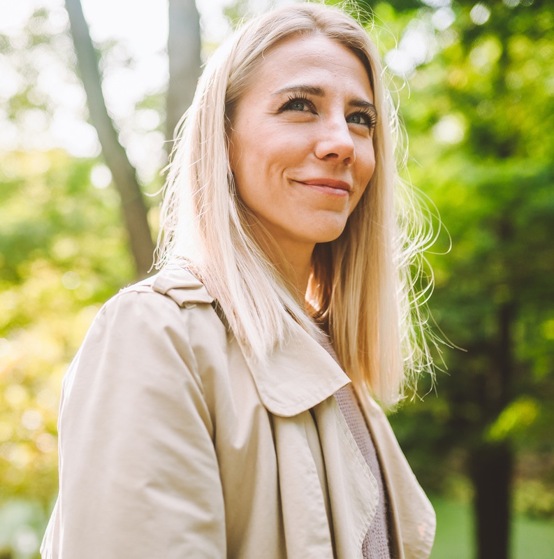 Caucasian blonde woman smiling happily on sunny summer or spring day outside walking in park