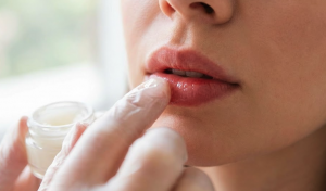 Person gently applying balm to lips after filler treatment