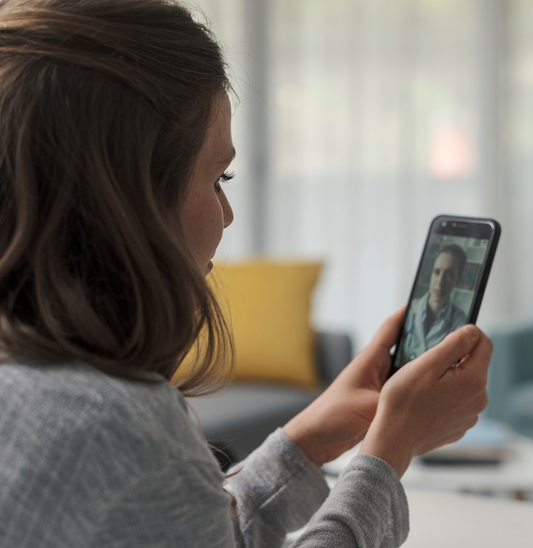 Photo of a woman on her phone receiving telehealth services
